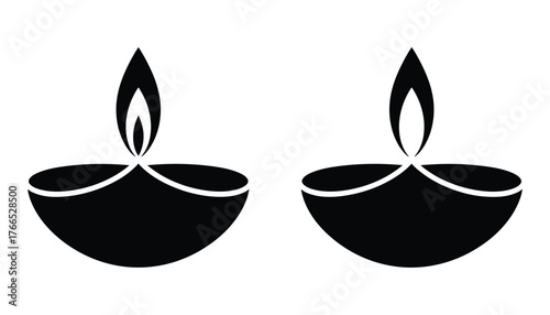 Two black diya oil lamps with flames on white background fire