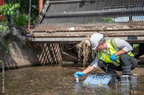 Environmental engineer collect water samples from drainage canals around the city and quality test