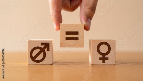 Hand places equality symbol between male and female gender symbols on wooden blocks