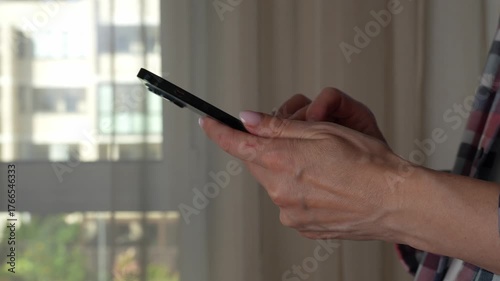 Woman using smartphone pressing fingerers, reading social media internet, typing text or shopping online. A close-up of hands holding a smartphone at home or work. 