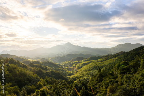 Fototapeta Naklejka Na Ścianę i Meble -  A Serene Morning in the Verdant Mountains with Sunlight Filtering Through the Clouds