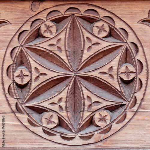 Carved wood architectonic detail of wall. Folklore decorative hexafoil motif.