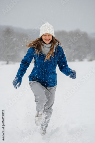 A young woman walking in winter forest. Happy traveler relaxing during trip enjoying snowy weather. Enjoying winter fresh air