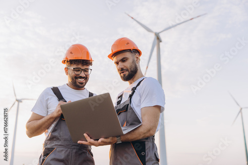 Engineers working on a wind turbine using a laptop for sustainable energy