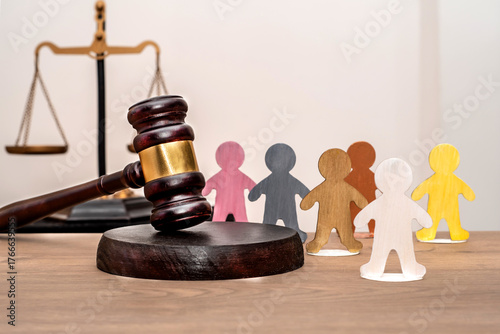 Judge's gavel next to various human figures against a backdrop of the scales of justice. Equality and inclusion before the law.