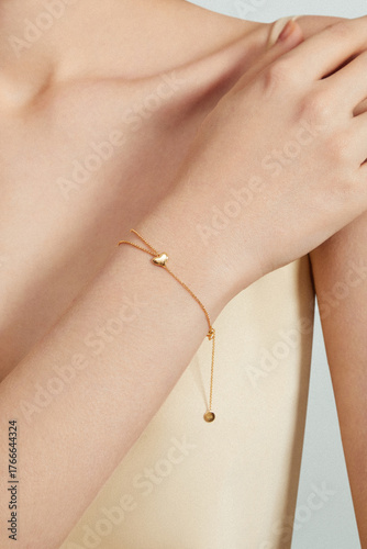 Close-up of a woman wearing a gold bracelet on her elegant arm.