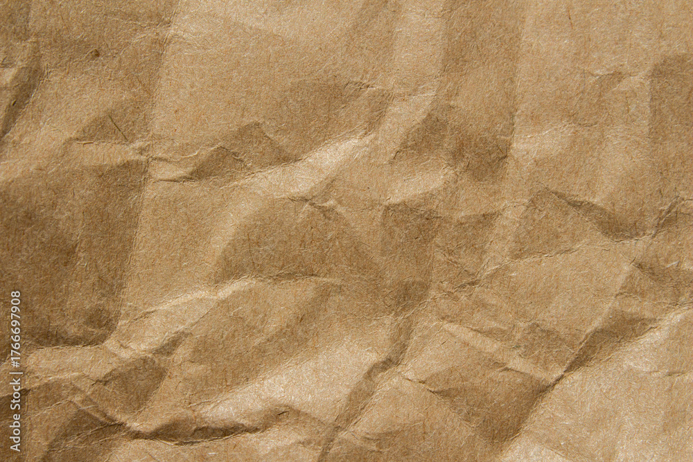 Obraz premium Brown crumpled kraft paper texture with deep folds and creases