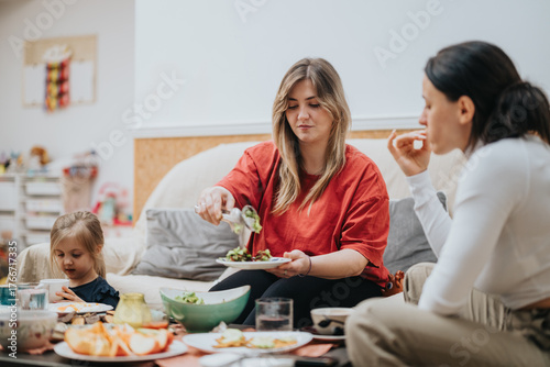 Фотография Two women and a young girl share a meal in a lively and cozy home environment
