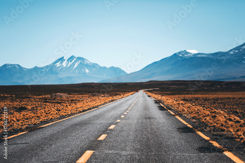 open road in the middle of the atacama desert, chile, with volcanoes all around