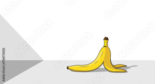 Bright yellow banana peel lying on clean surface, with shadow cast by geometric shape, evoking humor, slip hazard, or simple still life composition