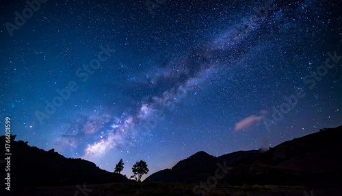 Panoramic night view of the milky way over silhouetted hills and trees