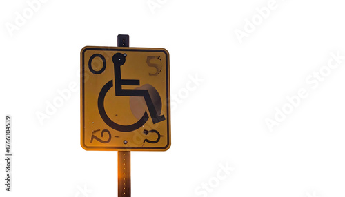 Yellow accessible sign illuminated in dark, depicting a person in wheelchair for disability access