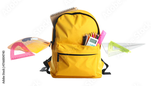 Yellow backpack with school supplies like pencils, calculator, and ruler against a black backdrop
