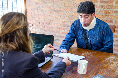 Mature adult female lawyer assist a injured man with legal problem. Lawyer showing document. Compensation for work or car accident. Legal concept. Social Worker.