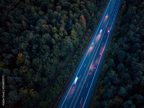An aerial view of the highway traffic at night between the autumn forest