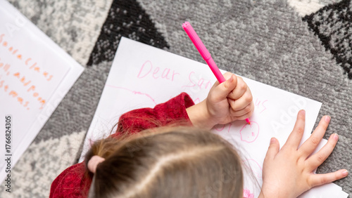 Two cute little girls sisters write letter to Santa lying on floor at home in Christmas decorated room