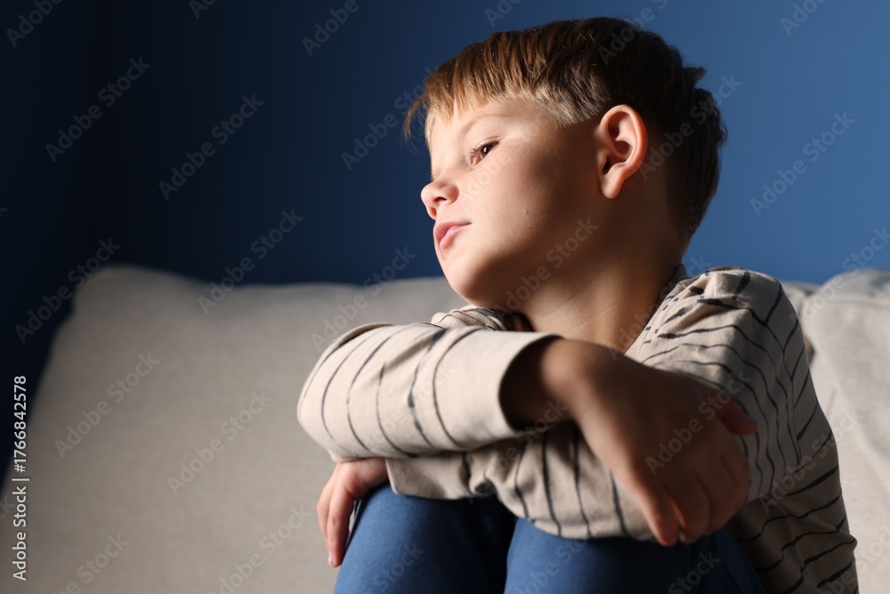 © New Africa - Upset little boy sitting on sofa indoors, space for text © New Africa - Upset little boy sitting on sofa indoors, space for text