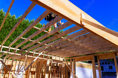 Fotografija Workers are constructing wooden roof frame in residential area under framework c