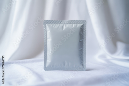 Silver sachet package mockup on white fabric background for product presentation