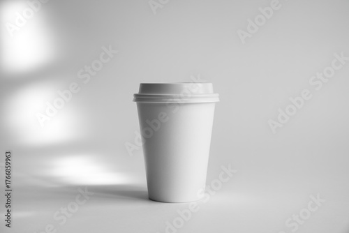 Simple white paper coffee cup with lid on a white background in soft studio light