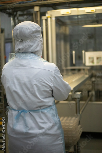Worker on the conveyor. A worker in a white coat. Food production.