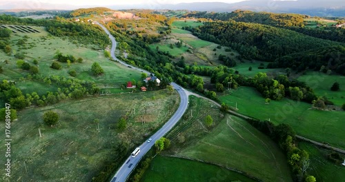 Aerial view of a winding country road through green hills