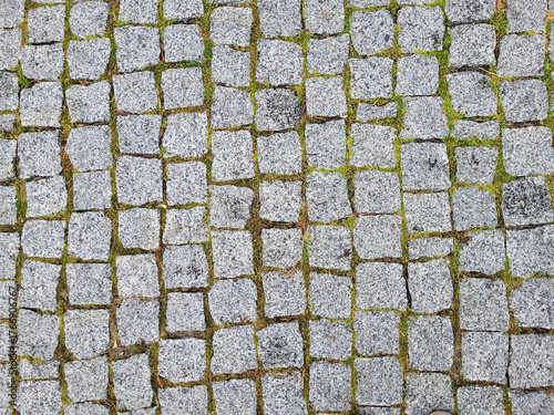 The old pavement made of gray granite tiles in the city square