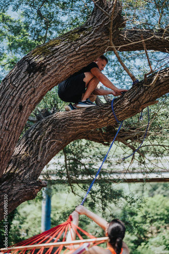 A tree-climbing activity with a person securing a hammock underneath, set in nature. Trees and greenery provide a natural and adventurous backdrop, emphasizing outdoor recreational pursuits.