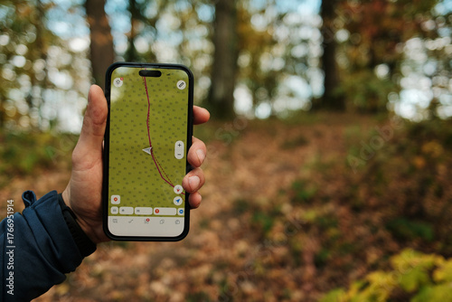 Close-up of man holding smartphone with GPS navigation app while hiking in autumn forest of Fruska Gora National Park Serbia. Travel concept