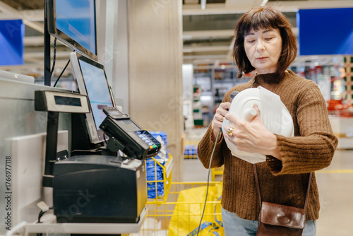 Senior woman scanning item with barcode reader at self service counter