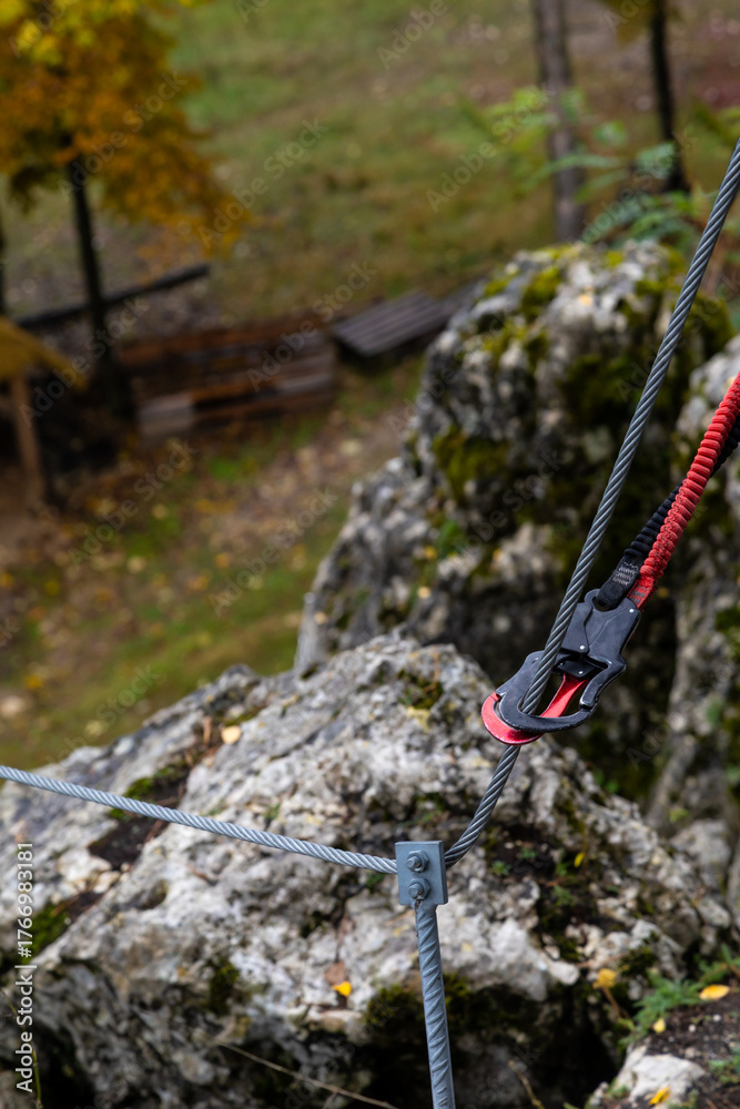 Naklejka premium Double carabiner attached to a steel safety rope during climbing.