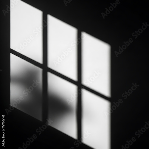 Geometric light and shadow patterns cast by window panes on a dark wall