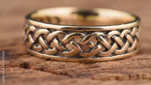 Close Up Gold Ring with Intricate Knot Design on Weathered Wooden Surface