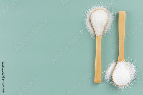 Stevia powder, white sugar in wooden spoons on a green background. Natural and artificial sweeteners. Copy space