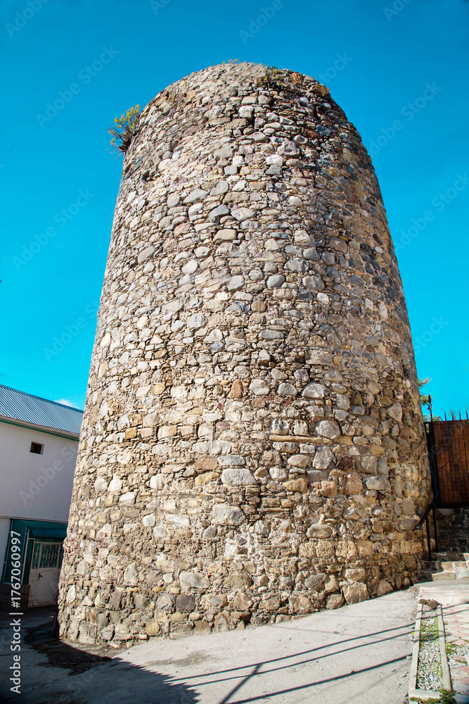 Naklejka premium The tower of the ancient fortress of Aluston against the background of the blue sky on a clear sunny day, Russia. Medieval architecture, world tourism.