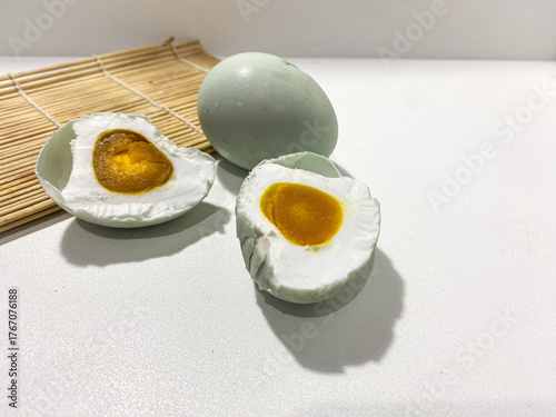 Salted egg isolated on white background. Half salted egg and whole preserved duck egg on white surface. Salted duck egg photography isolated on clean background. Boiled half and whole egg.