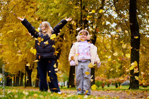 Children playing in autumn park with leaves