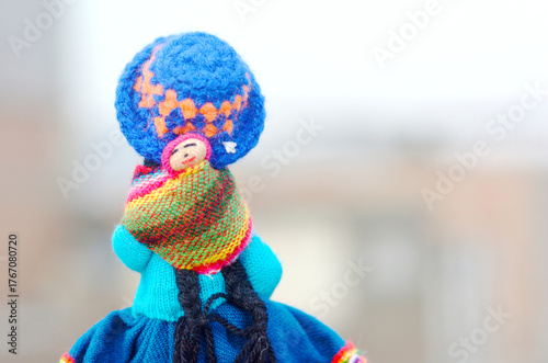 Handicraft doll carrying baby in the sling.