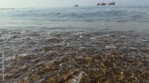 Slow motion as sea waves crash against the sandy shore. Coastal area. Relaxing summer sea background