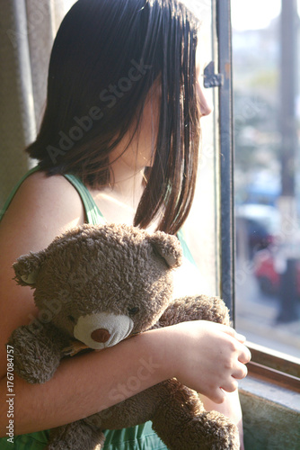 Preteen girl holding a teddy bear.