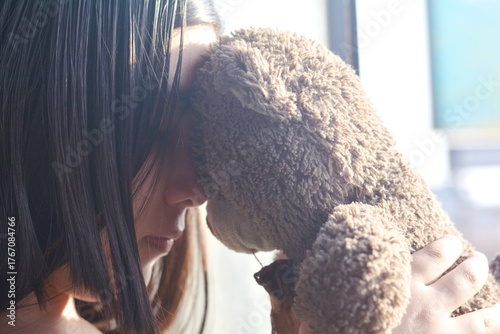 Preteen girl holding a teddy bear.