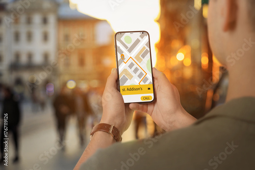 Man using app on mobile phone to call taxi on city street, closeup