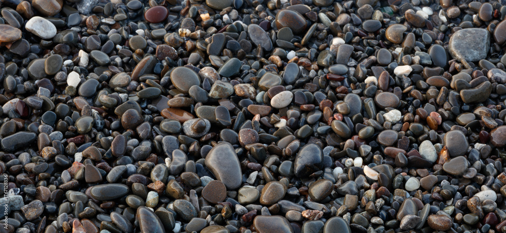 Naklejka premium Wet Pebbles stones on seashore as texture background for design web banner template page. SPA concept background.