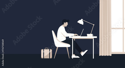 Man working on laptop at desk in dark room with lamp and suitcase, focused on work with a minimalist and modern aesthetic.