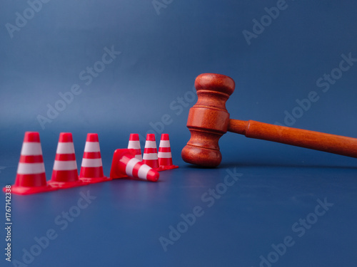 The combination of a gavel and traffic cones can symbolize legal obstacles or the law creating barriers