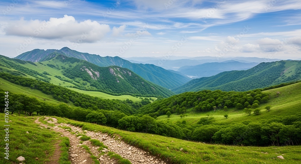 Fototapeta premium Majestic mountain landscape with lush green hills and a winding path under a blue sky