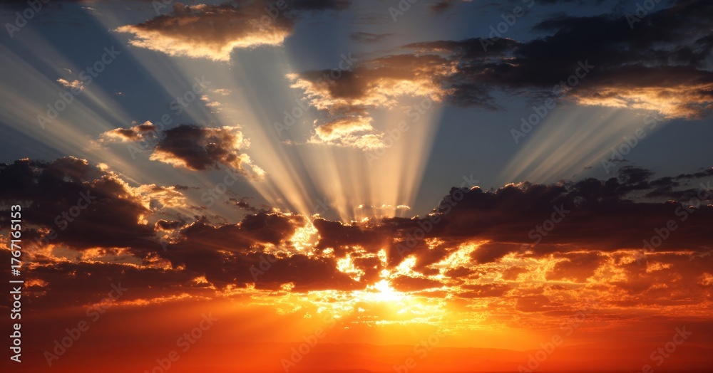 Fototapeta premium Sunlight streaming through clouds at sunset, casting a warm glow over the sky.