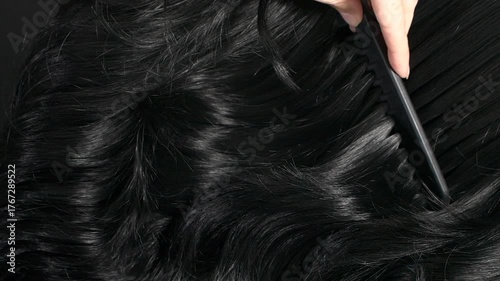 Closeup black hair texture, slow motion of female hand combing long curly hair