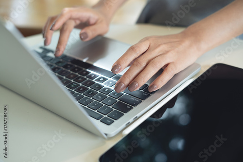 Photography Close up of woman hands typing on laptop computer with digital tablet on table,