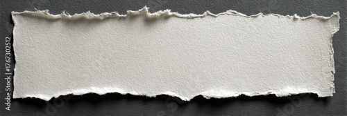 A ripped piece of off-white paper against a dark gray background